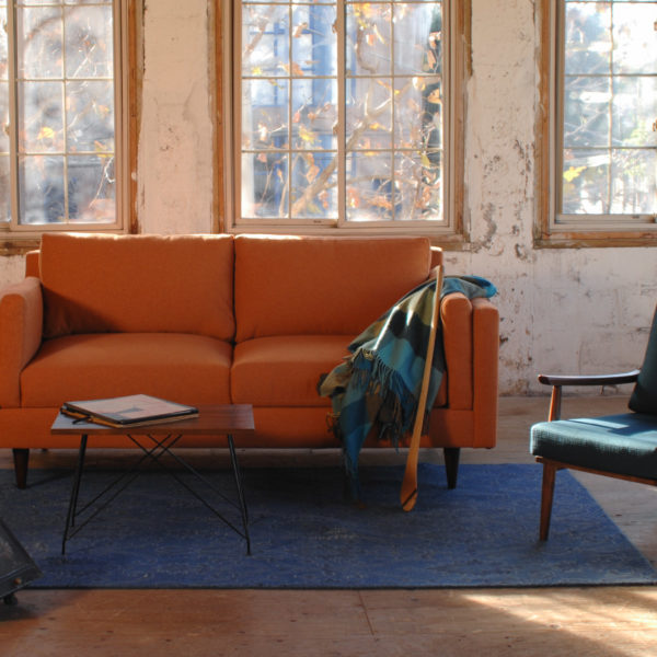 orange mid century modern style sofa in a living room with decor