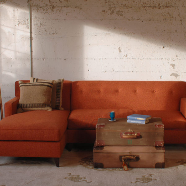 red mid century modern style sofa in a living room with furniture and decor