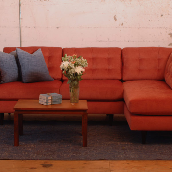 red mid century modern style sofa in a living room with furniture and decor