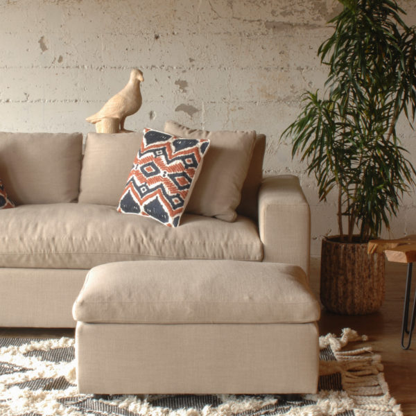 cream colored sofa and ottoman in a living room with furniture and decor