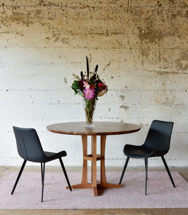round wood dining table and black leather chairs