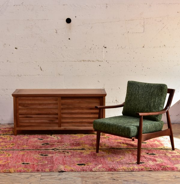 wood media cabinet and green armchair