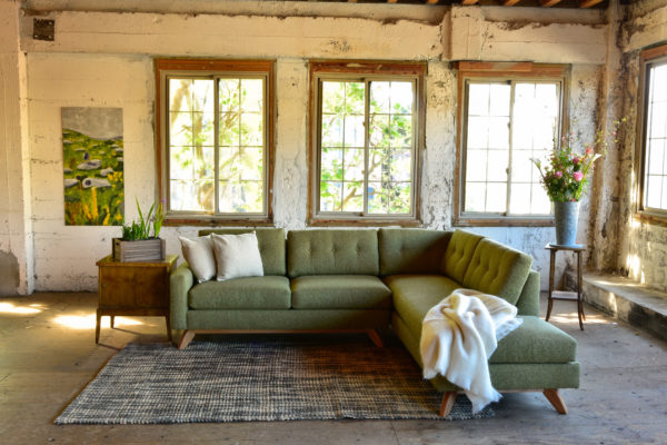 Green sofa in living room with decor and plants