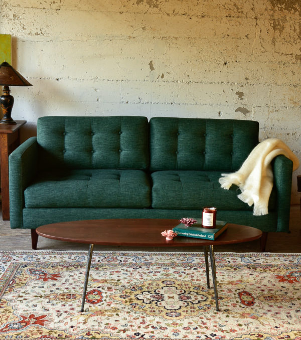 Green mid century modern style sofa in a living room with decor