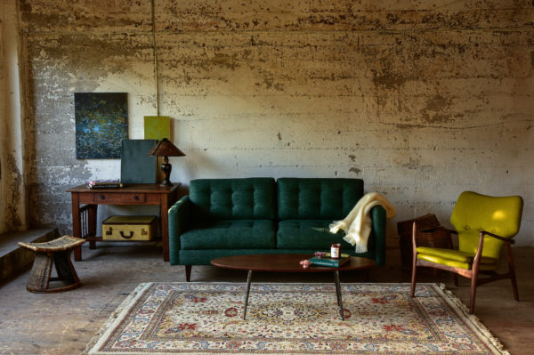 Green mid century modern style sofa in a living room with decor