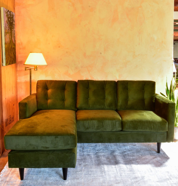 green velvet sofa with chaise in a living room with plants and decor