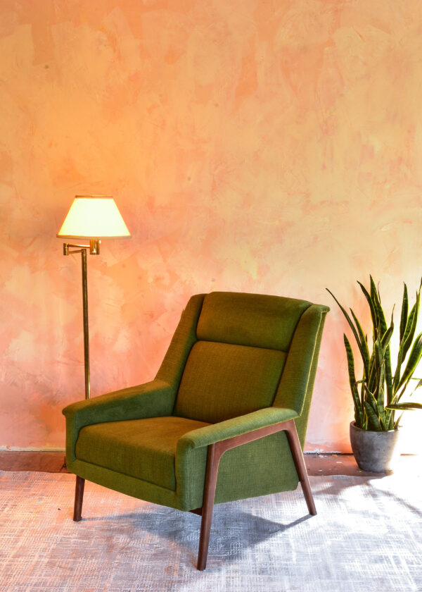 green arm chair in a living room with decor and plants